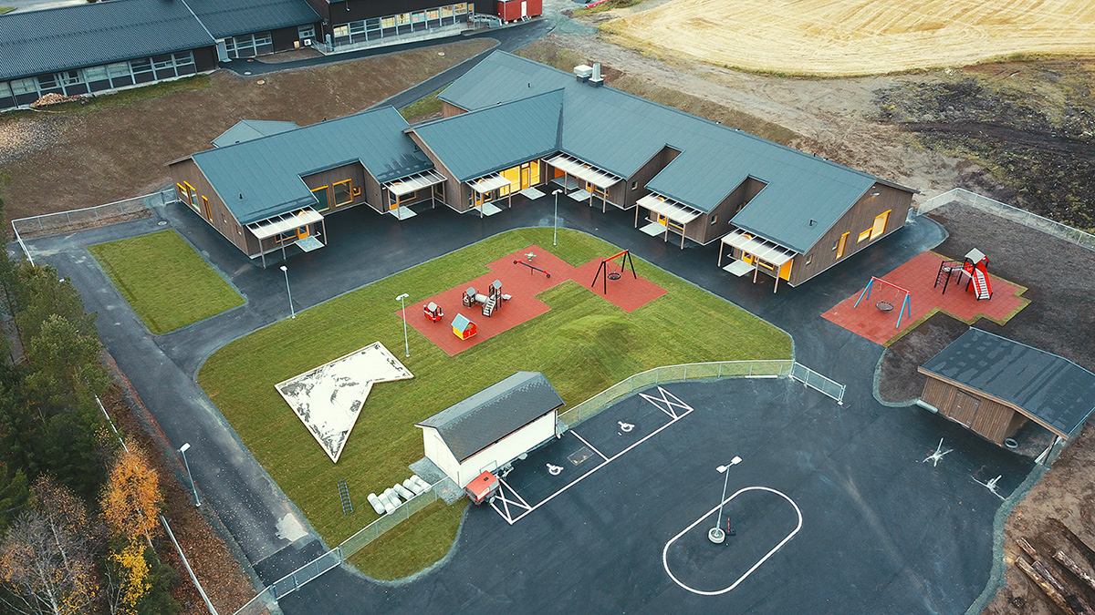 VB-rørlegger Harald Larsen. Luftfoto av nybygget Eid barnehage med lekeplass, grøntområder og parkering.